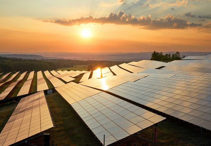 Placas solares en el campo con el cielo atardeciendo y el sol incidiendo sobre ellas