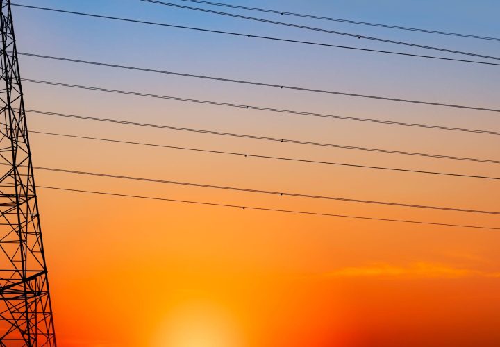 Silhouette high voltage electric pylon and electrical wire with an orange sky. Electricity poles at sunset. Power and energy concept. High voltage grid tower with wire cable at distribution station.